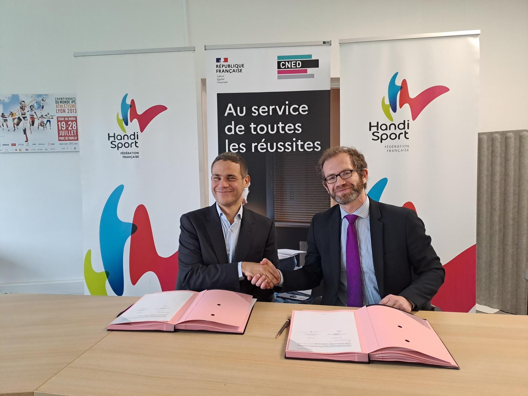 Photo montrant les deux directeurs au moment de la signature et échangeant une poignée de main.